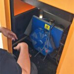 Technician inspecting a diesel generator alternator for overheating