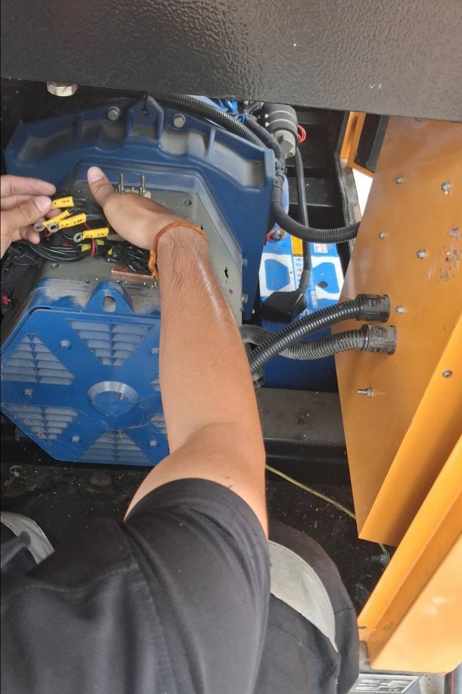 Technician inspecting diesel generator alternator terminal connections